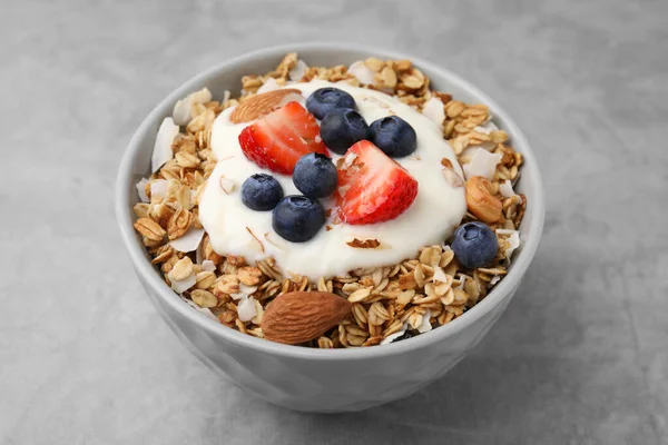 味道鲜美的格拉诺拉 酸奶和新鲜的浆果放在浅灰桌子上的碗里 健康早餐 — 图库照片