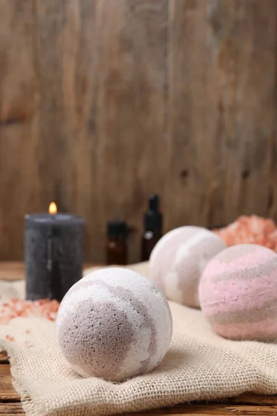 Bath bombs and burning candle on table, closeup. Space for text