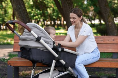 Parkta bebek arabasında küçük sevimli bir çocukla mutlu bir dadı.