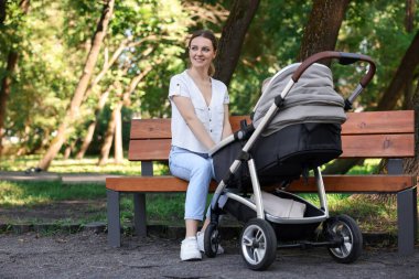 Bebek arabasıyla parkta mutlu bir dadı.