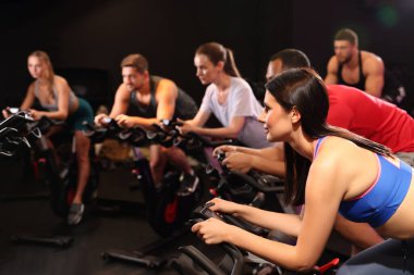 Spor salonunda egzersiz bisikleti eğitimi alan bir grup insan.