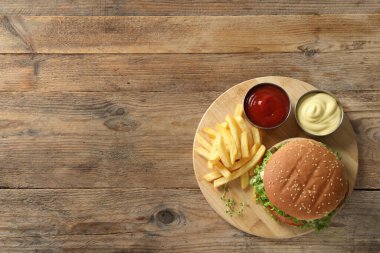 Biftek köfteli leziz burger, sos ve ahşap masada patates kızartması, üst manzara. Metin için boşluk