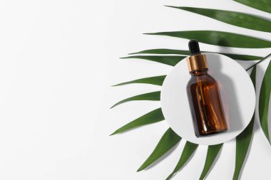 Beyaz arka planda kozmetik yağlı ve yeşil yapraklı bir şişe. Metin için boşluk