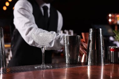 Barmen tezgahta martini bardağında taze alkollü kokteyl hazırlıyor.