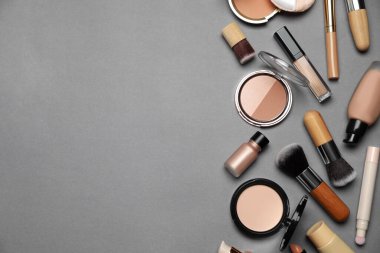 Yüz pudraları ve gri arka planda diğer makyaj ürünleri, düz. Metin için boşluk