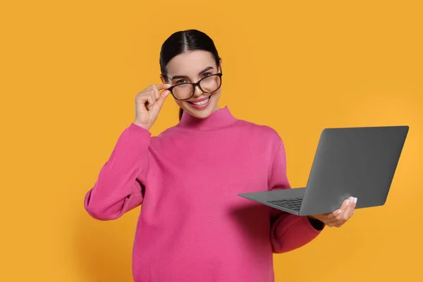 Happy woman with laptop on orange background