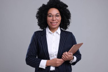 Gri arka planda tableti olan genç bir iş kadını