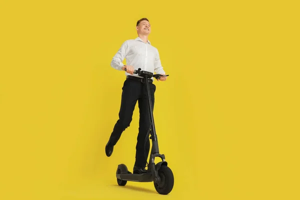 快乐男人骑着现代电动车在黄色的背景下 低角度的视野 — 图库照片