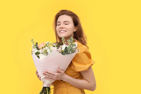 黄色の背景に美しい花の花束を持つ幸せな女性 — ストック写真
