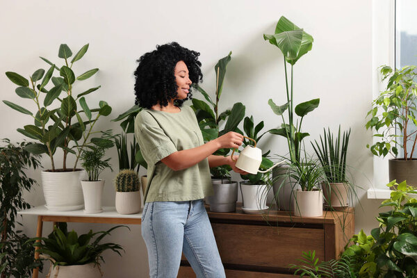 Счастливая женщина поливает красивые горшки комнатные растения дома