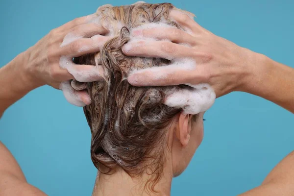 在浅蓝色背景上洗头的女人 — 图库照片