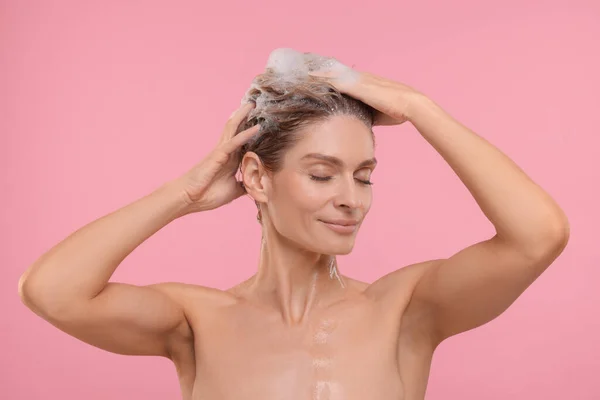 漂亮的女人在粉色背景下洗头发 — 图库照片