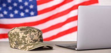 Askeri eğitim. Kaptan ve laptop ahşap masada ABD bayrağına karşı.