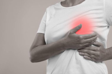 Gri arka planda göğüs muayenesi yapan kadın, yakın plan. Renk aksanı efekti