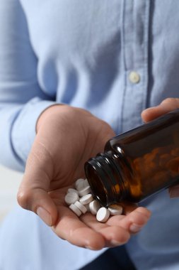 Şişeden haplar döken kadın, yakın çekim görüntüsü.