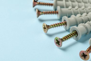 Açık mavi arka planda birçok metal vida, yakın plan. Metin için boşluk