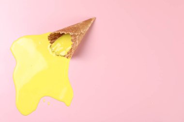 Pembe arka planda erimiş dondurma ve gofret külahı. Metin için boşluk