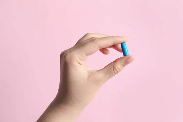 stock image Woman holding pill on pink background, closeup