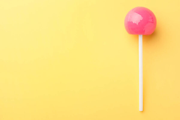 One tasty lollipop on yellow background, top view. Space for text