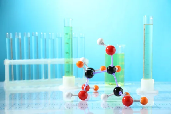 Molekularmodell Und Laborgläser Auf Spiegeloberfläche Vor Hellblauem Hintergrund — Stockfoto