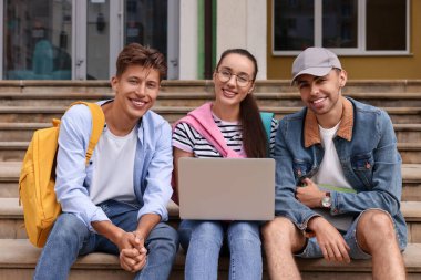 Dışarıda dizüstü bilgisayarla ders çalışan mutlu genç öğrenciler.