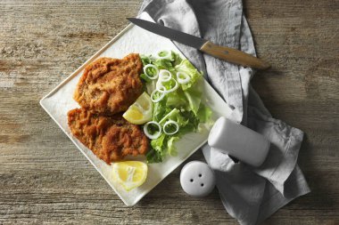 Lezzetli şnitzeller limon ve salata ile servis edilir ahşap masa, düz yatar