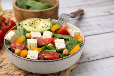 Bir kase lezzetli salata, soya peyniri ve sebzeler beyaz ahşap masada, yakın plan. Metin için boşluk