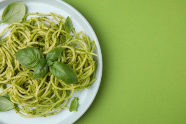 Pesto soslu lezzetli makarna ve açık yeşil arka planda fesleğen, üst manzara. Metin için boşluk