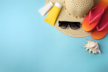 Açık mavi arkaplanda plaj aksesuarları ve güneş kremi, metin için yeri olan düz bir yer.