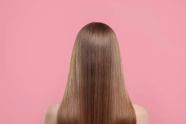 Woman with healthy hair on pink background, back view