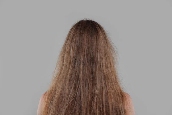 ライトグレーの背景 バックビューで髪を損傷した女性 — ストック写真