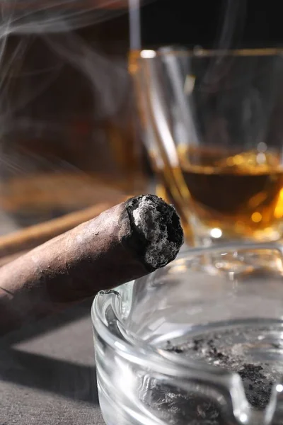 Aschenbecher Mit Glimmender Zigarre Und Whiskey Auf Grauem Tisch Nahaufnahme — Stockfoto