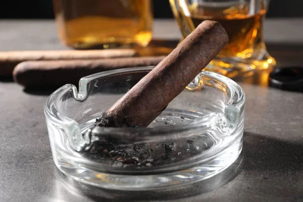 Aschenbecher Mit Glimmender Zigarre Und Whiskey Auf Grauem Tisch Nahaufnahme — Stockfoto