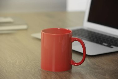 İşyerindeki ahşap masada kırmızı seramik bardak. Tasarım için model