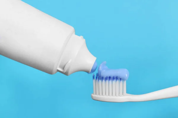 Het Aanbrengen Van Plakken Tandenborstel Tegen Lichtblauwe Achtergrond Close — Stockfoto