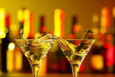 Martini bardaklarını şapırdatarak kokteyl ve zeytinlerle bardakları doldurarak.