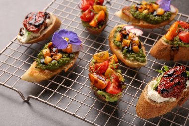 Farklı malzemelerle nefis bruschettalar ve gri masada balzamik sirke, yakın plan.