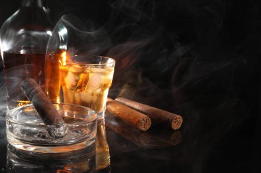 Smoldering cigar, ashtray and whiskey on black mirror surface. Space for text clipart
