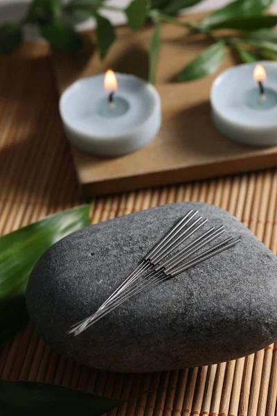 Stone with acupuncture needles on bamboo mat