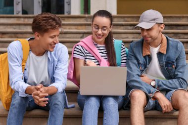 Dışarıda dizüstü bilgisayarla ders çalışan mutlu genç öğrenciler.
