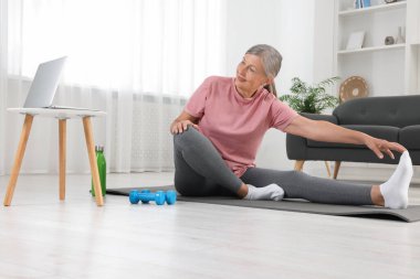 Spor giyim bölümündeki son sınıf kadın evde spor minderinde esniyor.