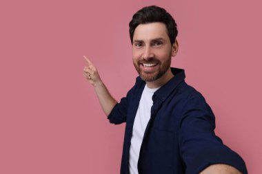 Gülümseyen adam pembe arka planda selfie çekiyor, mesaj için boşluk