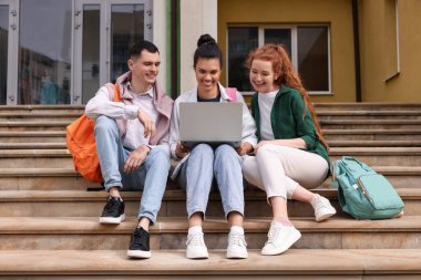 Dışarıda dizüstü bilgisayarla ders çalışan mutlu genç öğrenciler.