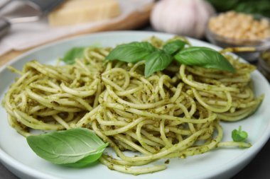 Pesto soslu lezzetli makarna ve tabakta fesleğen, yakın plan.