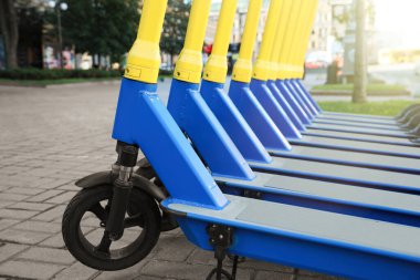 Birçok modern elektrikli scooter şehir caddesinde park halinde, yakın plan. Kiralama servisi