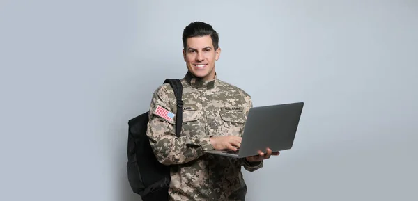 Military education. Cadet with backpack and laptop on light grey background