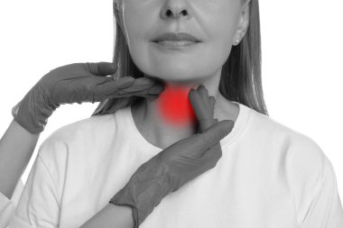 Endokrinolojist, beyaz arka plandaki hastanın tiroit bezini inceliyor, yakın plan. Renk aksanı efekti