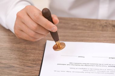 Ahşap masada belgeleri damgalayan adam, yakın plan