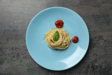 Gri masadaki domatesli ve peynirli leziz spagetti. Makarna yemeğinin enfes sunumu