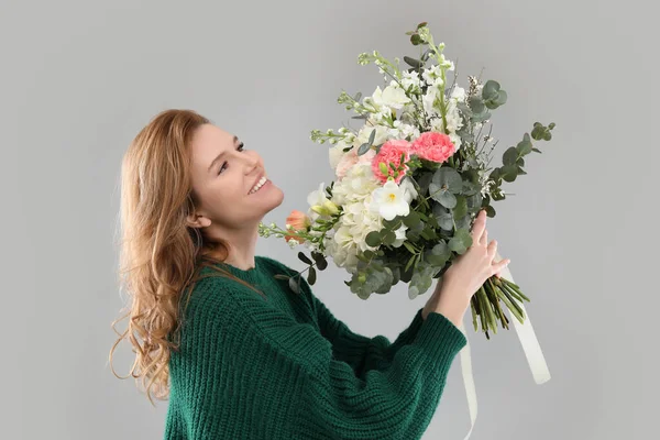 灰色の背景に花の花束を持つ美しい女性 — ストック写真